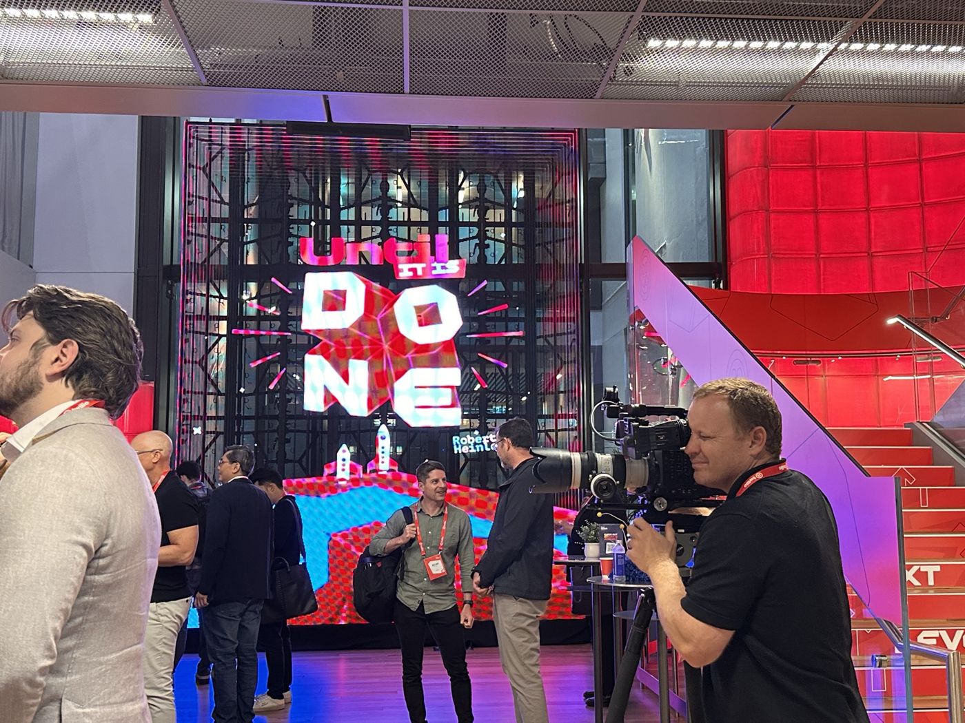 Attendees networking in front of a large LED screen at SIGNAL Sydney