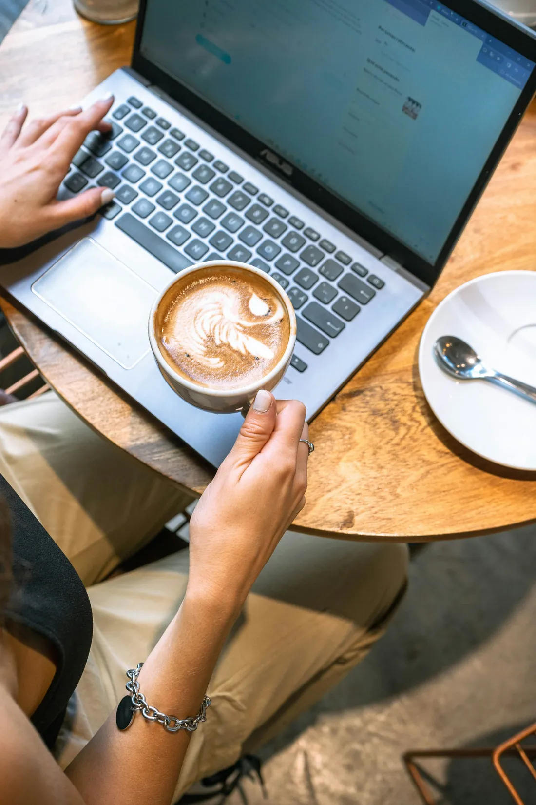 An owner checking the numbers on a laptop with a latte